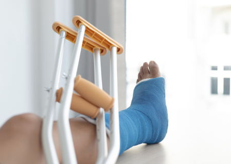 A leg in a blue cast with a pair of crutches resting on it.