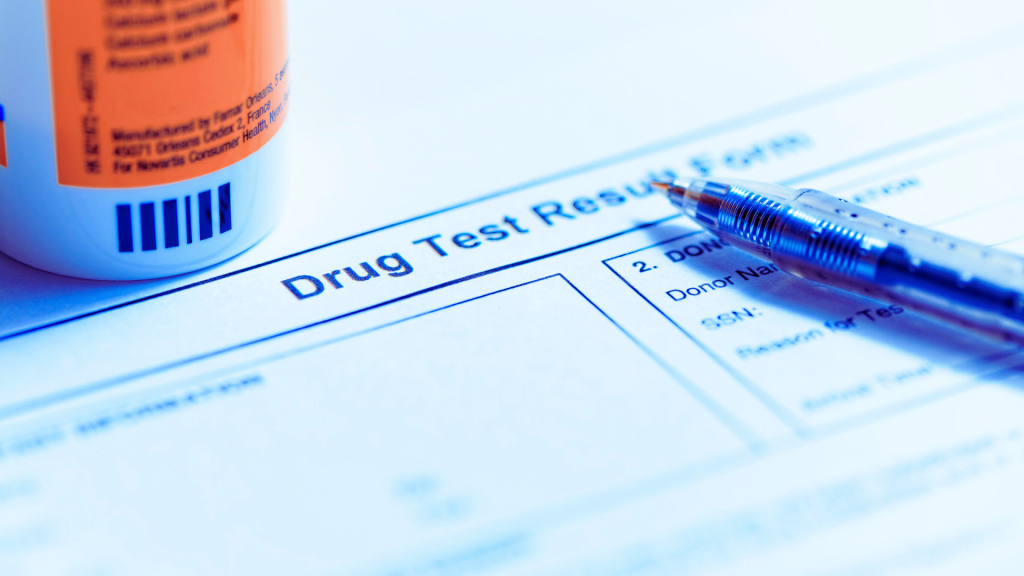 A "Drug Test Result Form" with a pen and the base of a pill bottle resting on it.